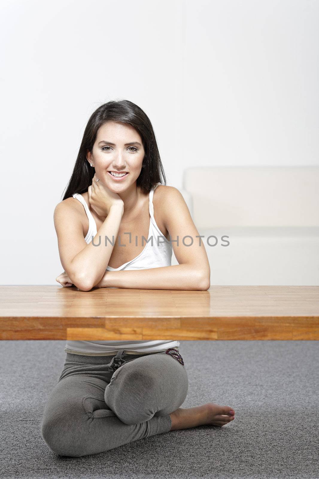 Beautiful young woman sitting next to a coffee table at home in casual clothes