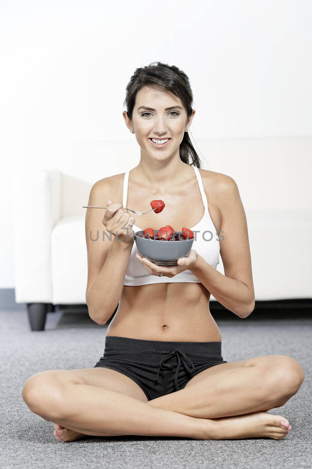 Woman ieating fruit in fitness clothes by studiofi