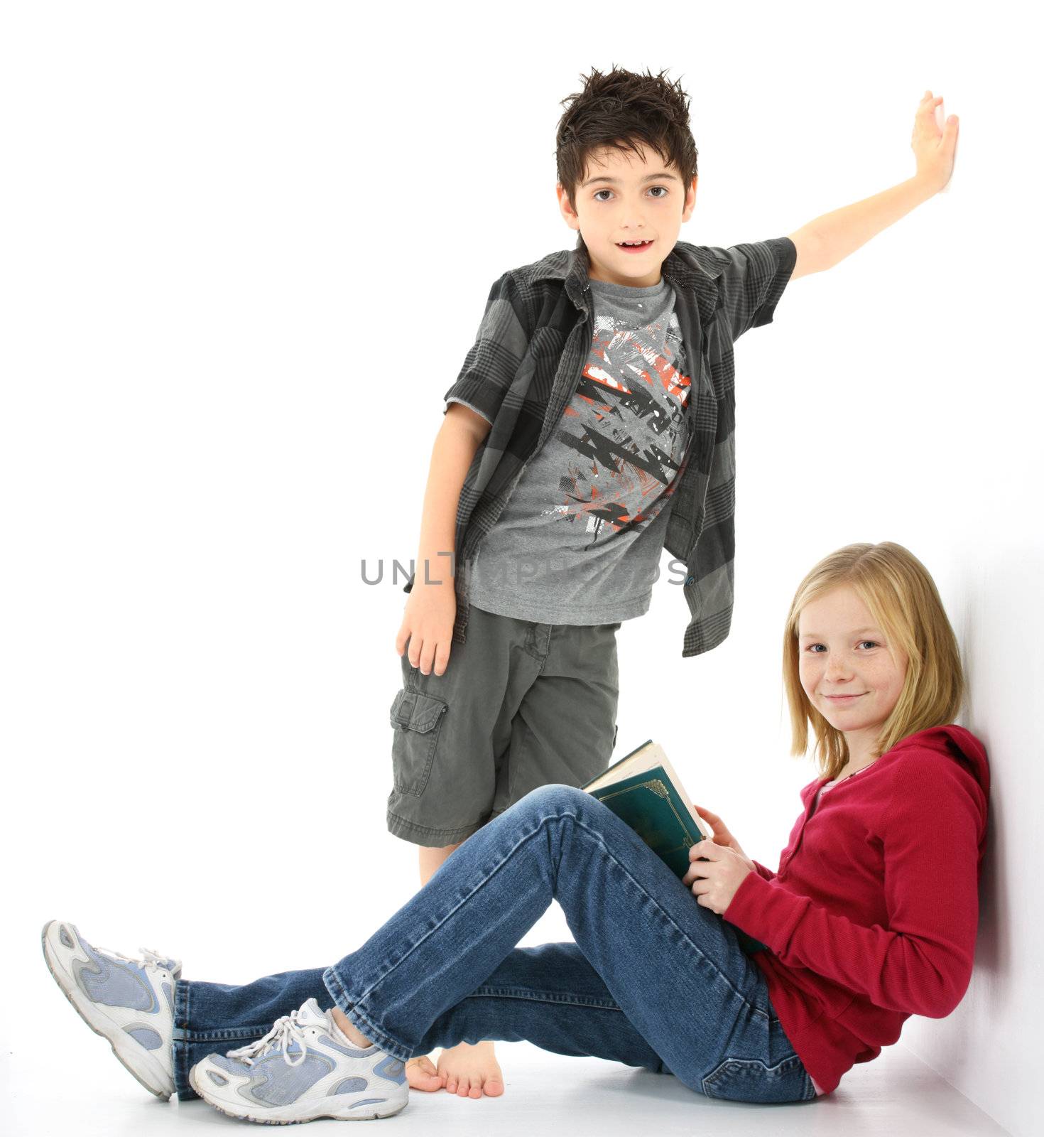 Beautiful young girl student with book sitting against the wall.  Boy standing behind her.