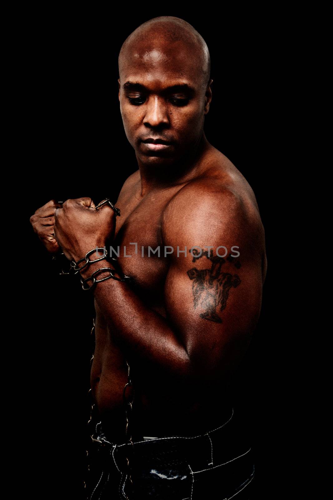 Attractive black bald man breaking chains over black background.