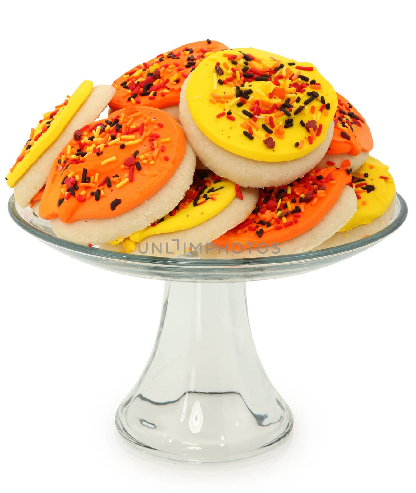 Orange and yellow autum decorated sugar cookies on glass platter over white.