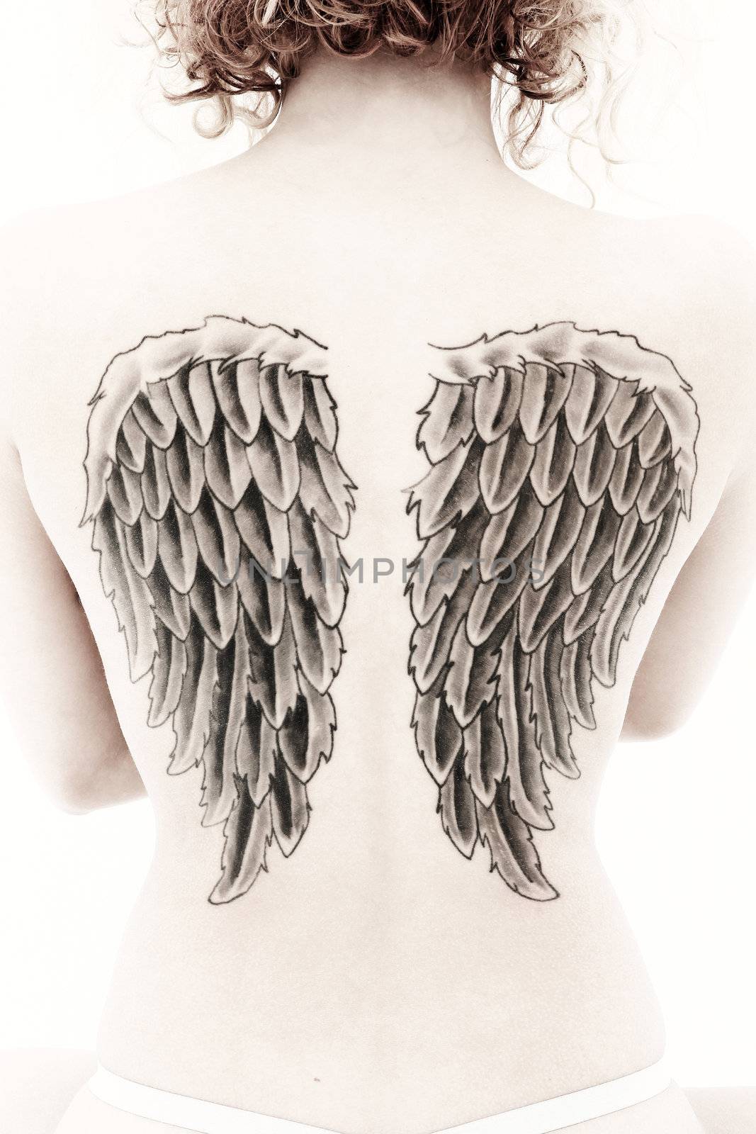 Sepia image of woman's back with large wing tattoos.