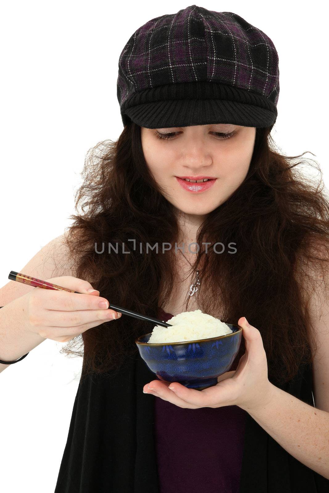 Attractive 18 year old young woman in hat eating bowl of rice with chopsticks over white.