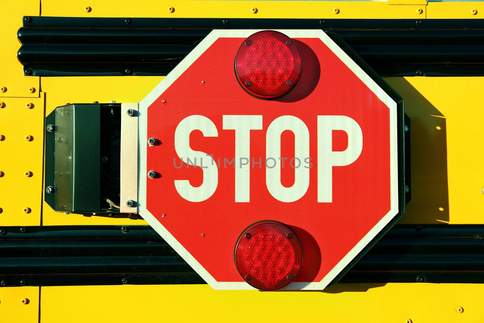 Close up of red stop sign on yellow school bus.