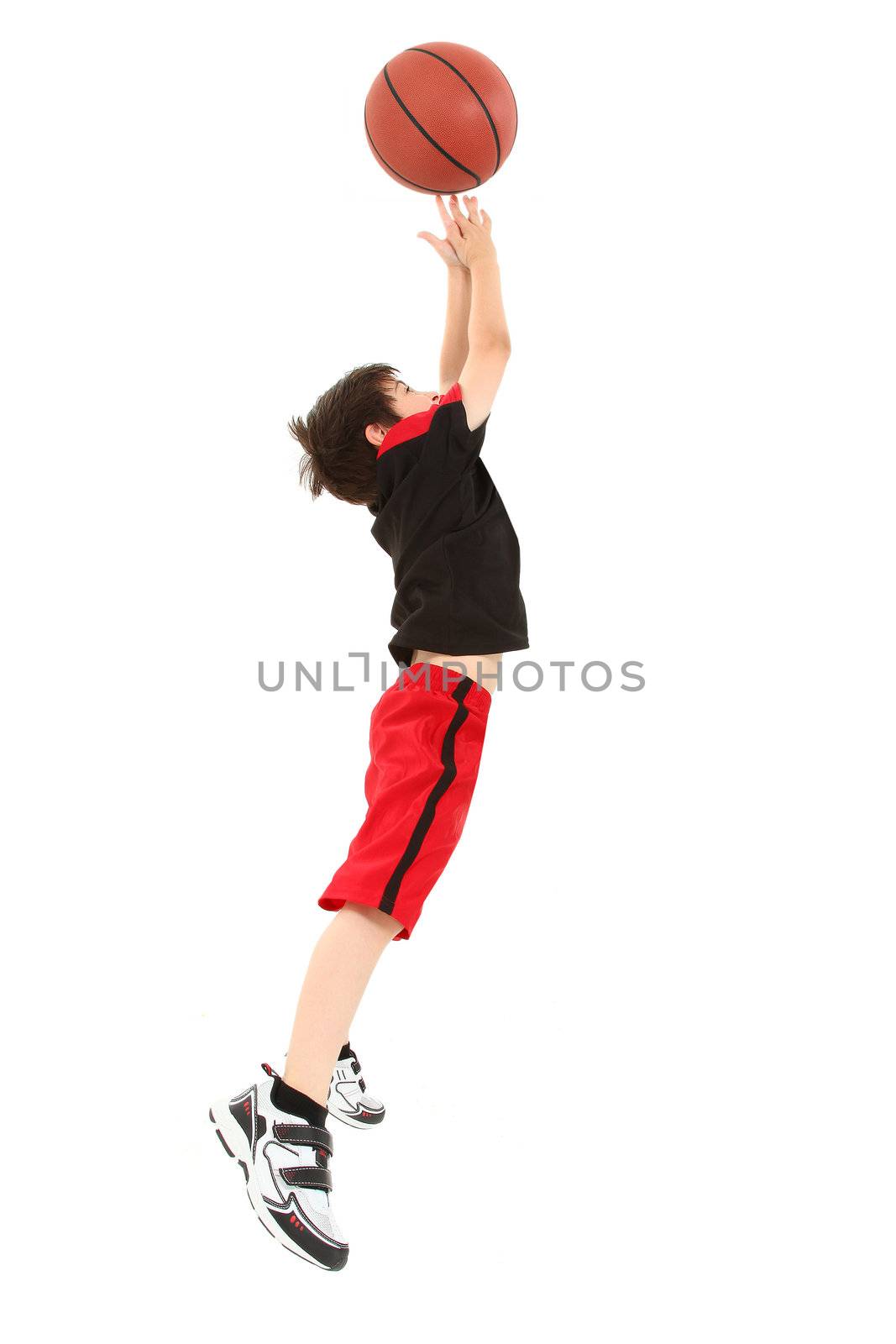 Energetic 8 year old boy child in basketball uniform jumping for shot.