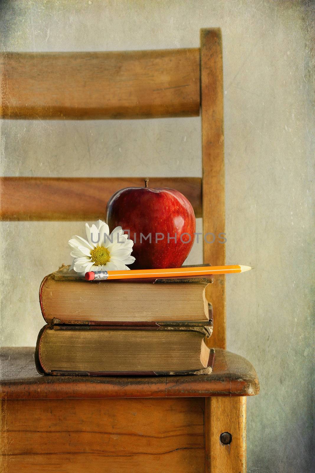 Apple and books on old school chair by Sandralise