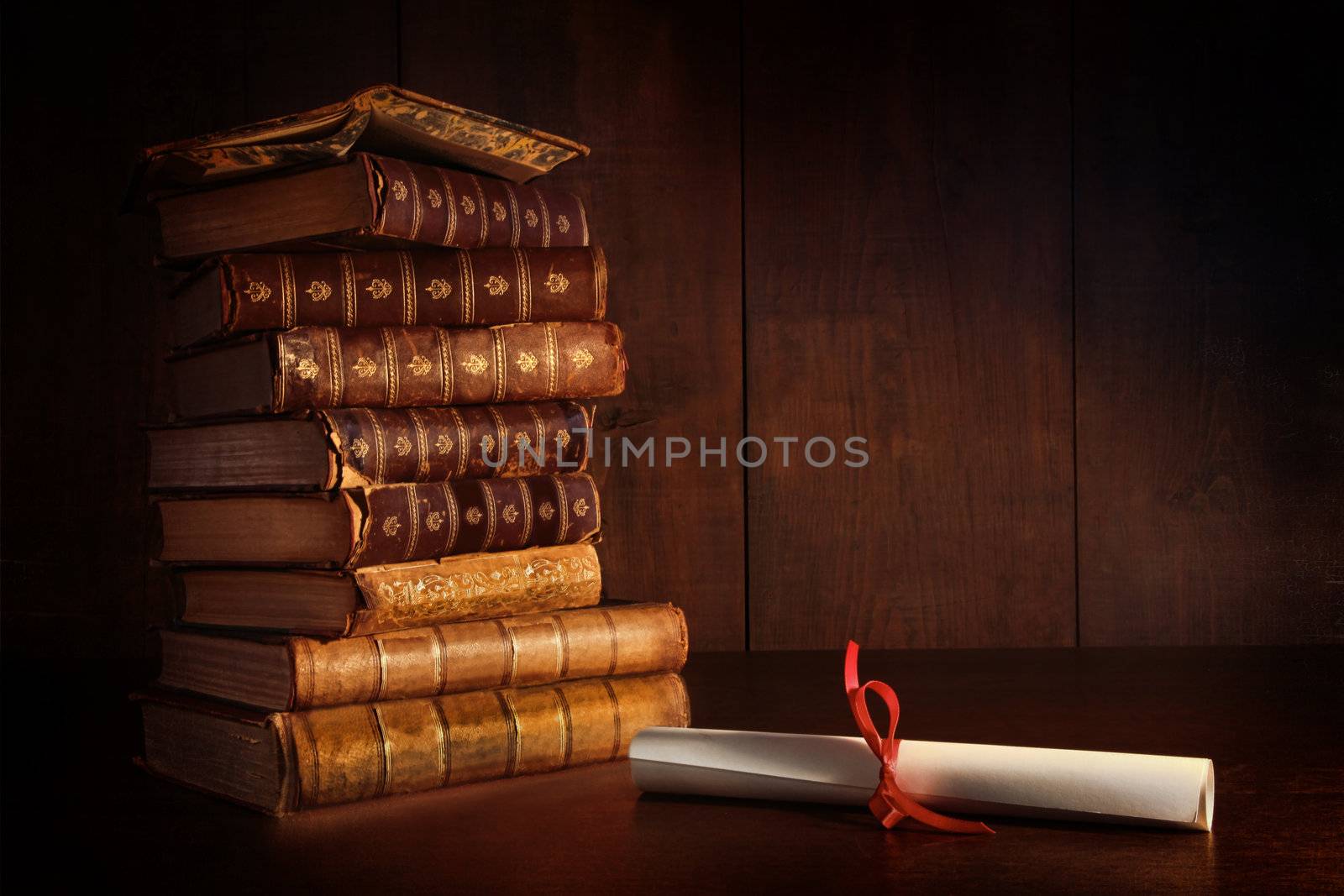 Pile of old books and diploma on desk