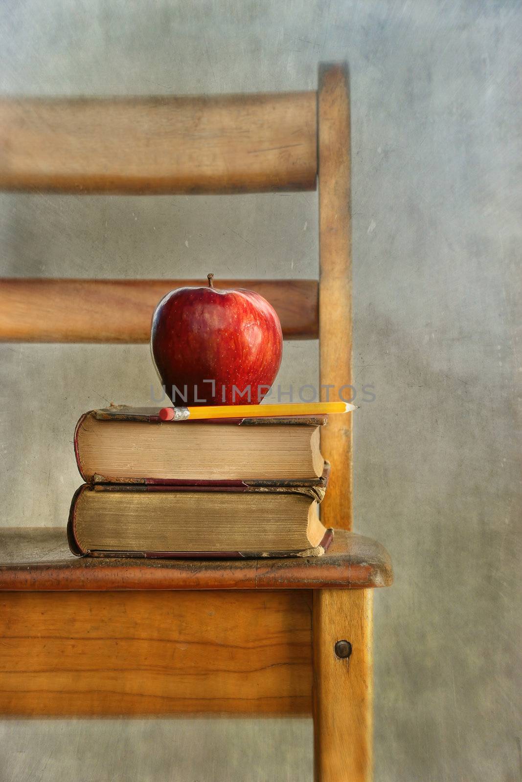 Apple and old books on school chair with vintage feel