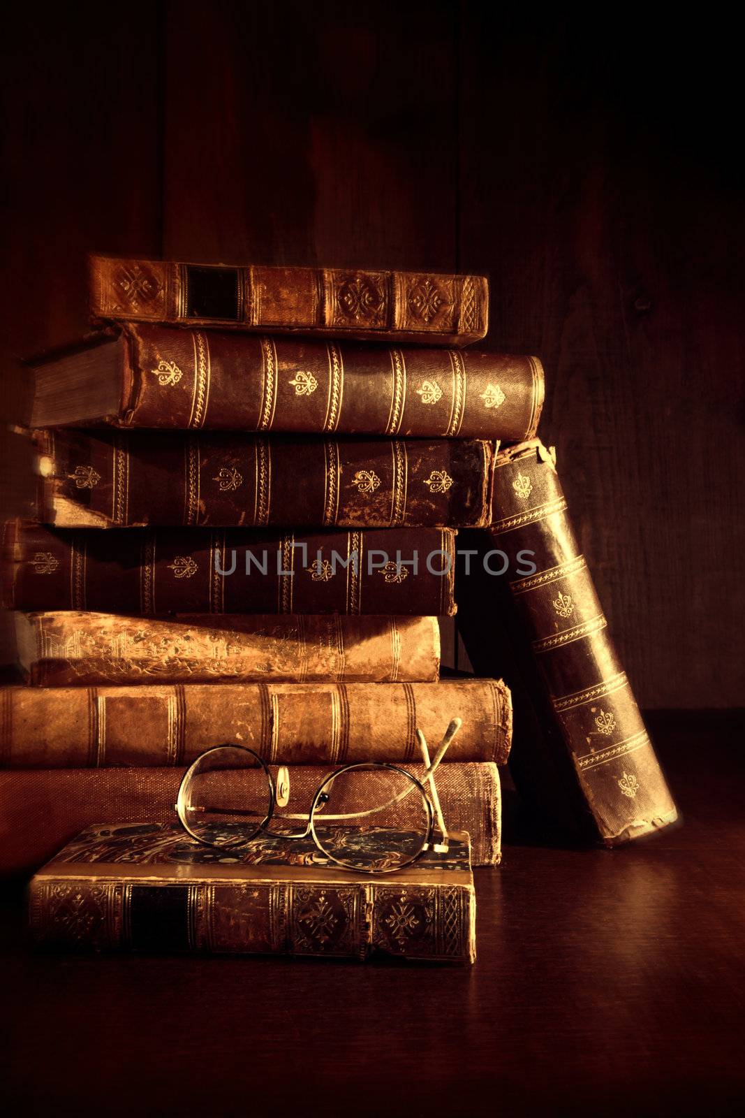 Stack of old books with reading glasses on desk