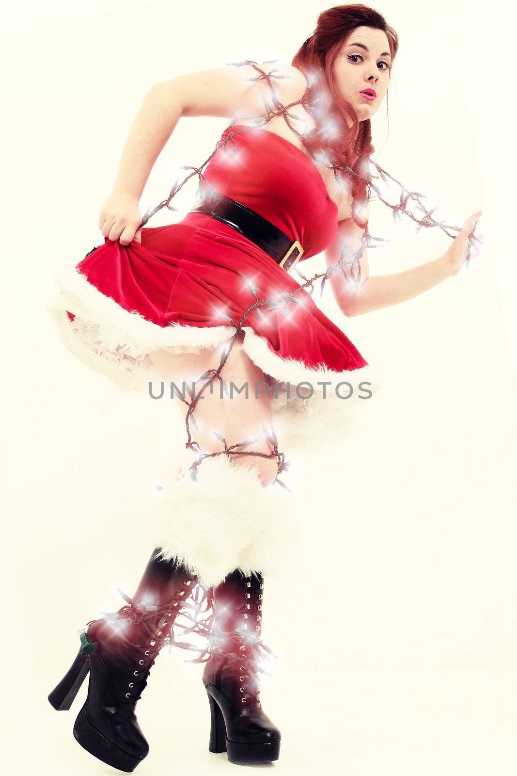 Beautiful sexy young woman tangled up in christmas lights. Retro style photography.