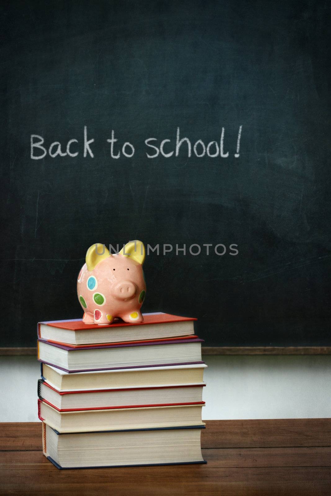 Piggy bank and books in front of chalkboard