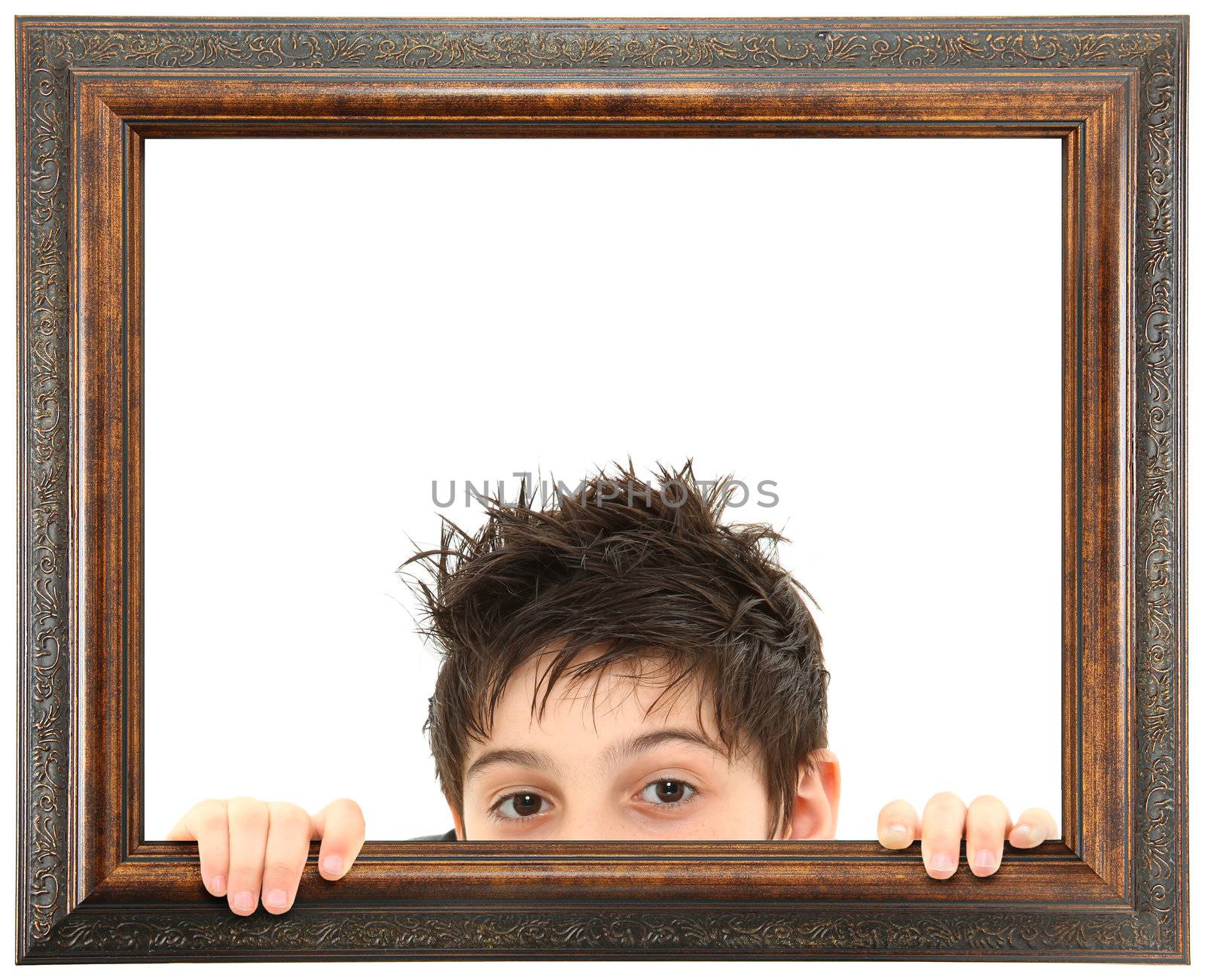 Attractive 8 year old boy peeking out of ornate stained wooden frame over white isolation.