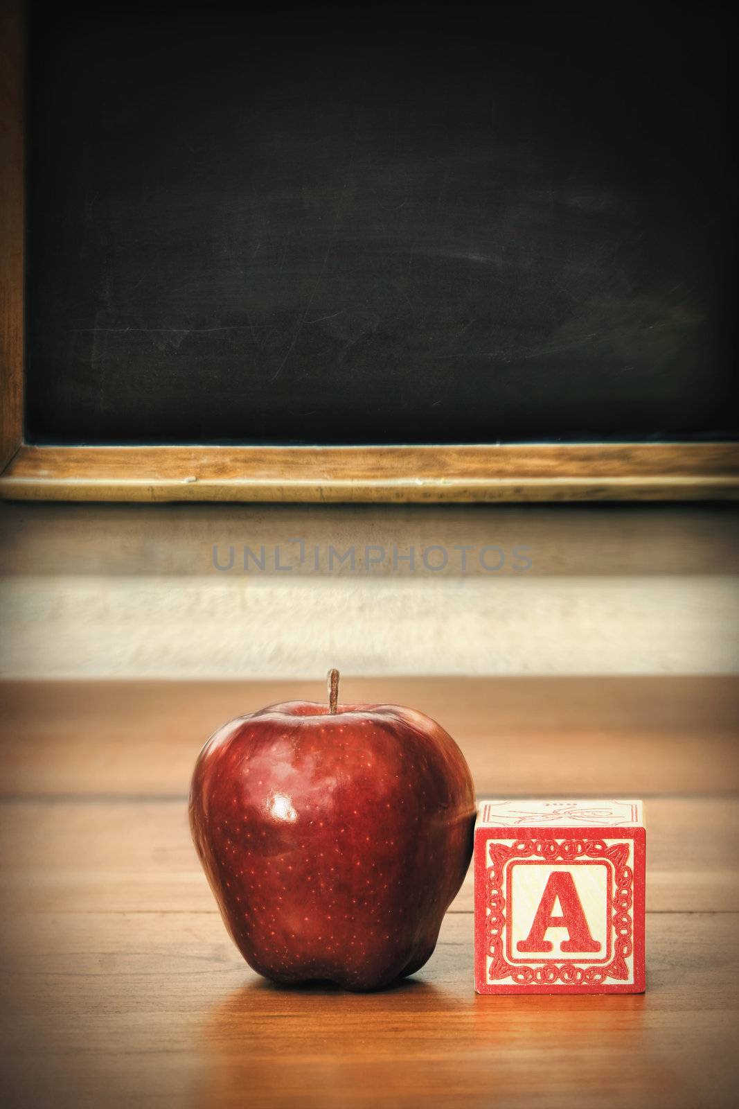 Delicious red apple on school desk by Sandralise