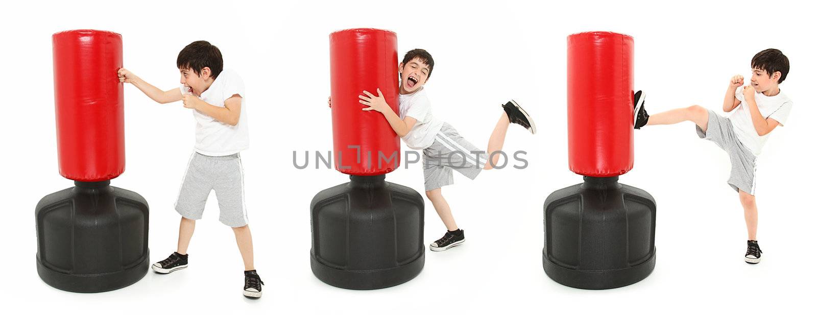 Adorable 8 year old boy practicing kicks and punches with a free standing heavy bag over white.