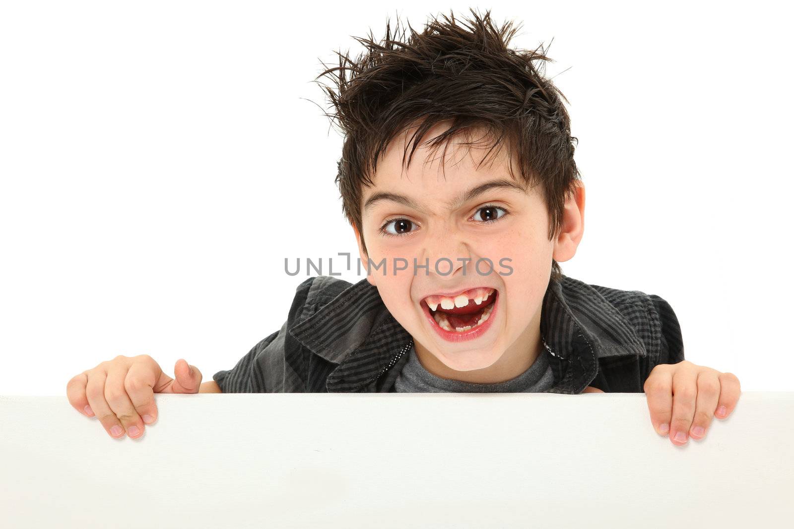 Adorable and funny 8 year old boy making silly animal face while holding blank canvas over white.