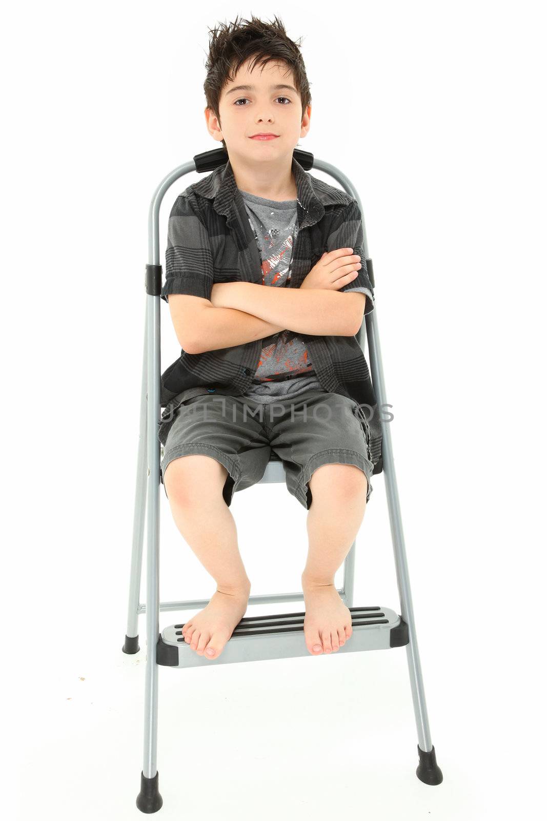 Attractive 8 year old boy child sitting with arms crossed on step ladder over white background.