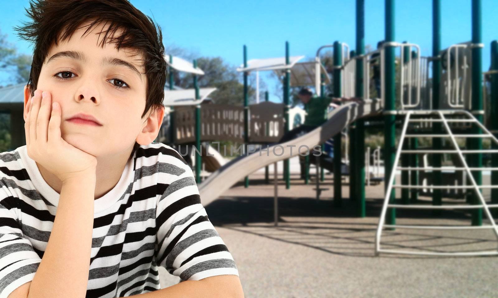 Handsome young boy child bored and waiting at park playground.