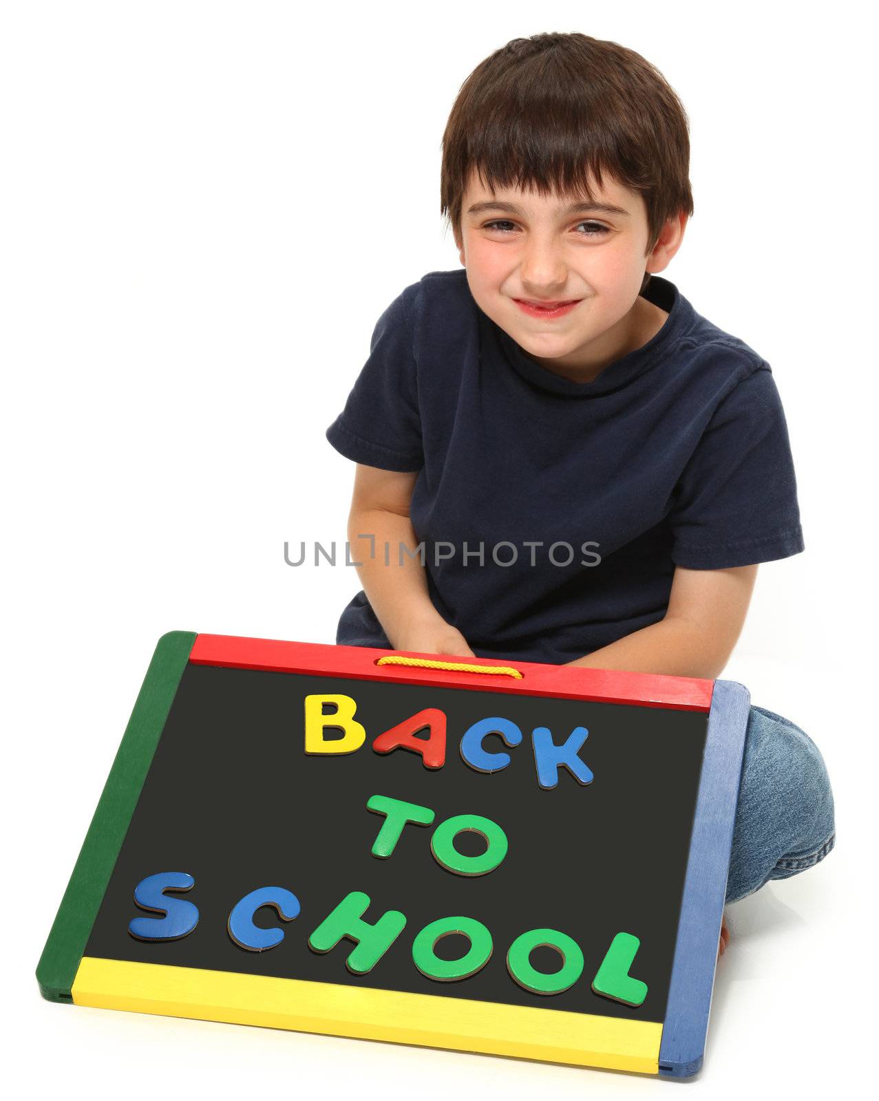 adorable seven year old boy holding back to school chalk board