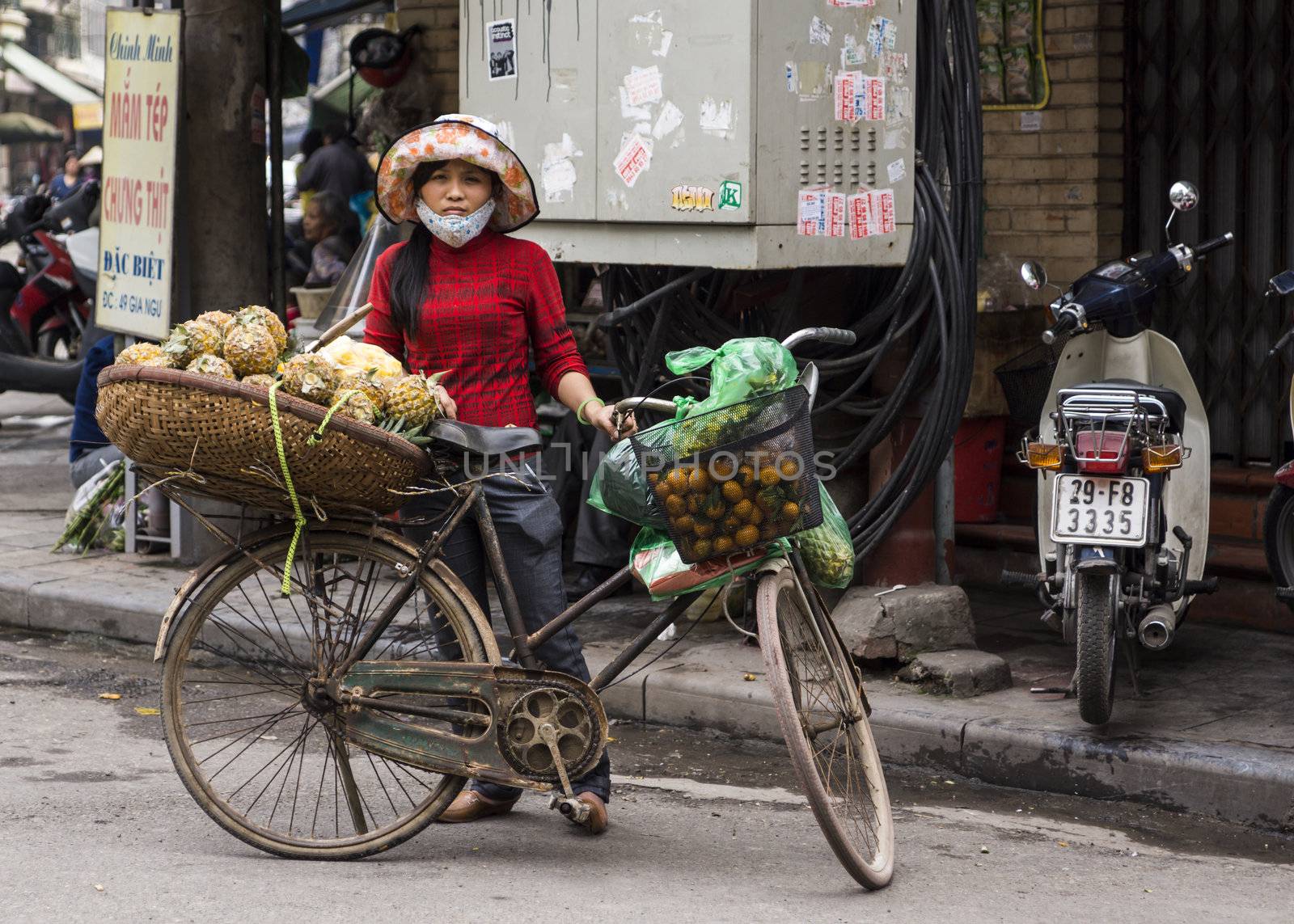 Street scene: young woman in red shirt with rusty bike.