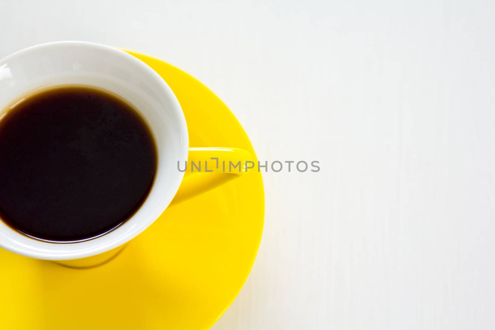 Black coffee in yellow cup and saucer