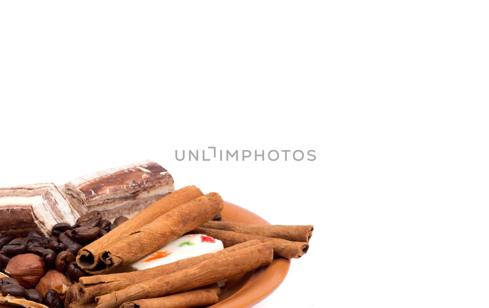 Sweets, cinnamon, nuts and coffee beans on a saucer isolated on white