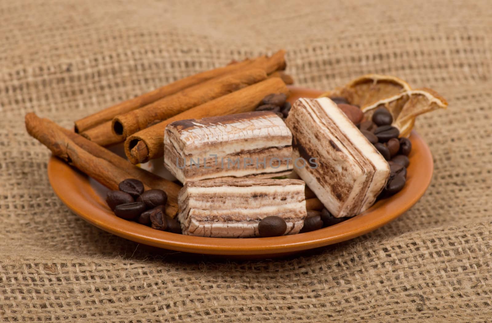 Sweets, cinnamon, nuts and coffee beans on a saucer.