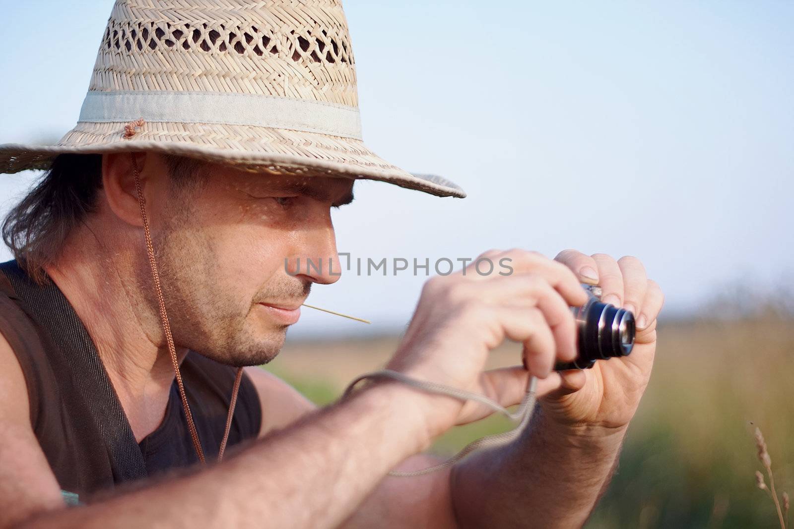 The man in a straw hat with the camera has a rest outdoors