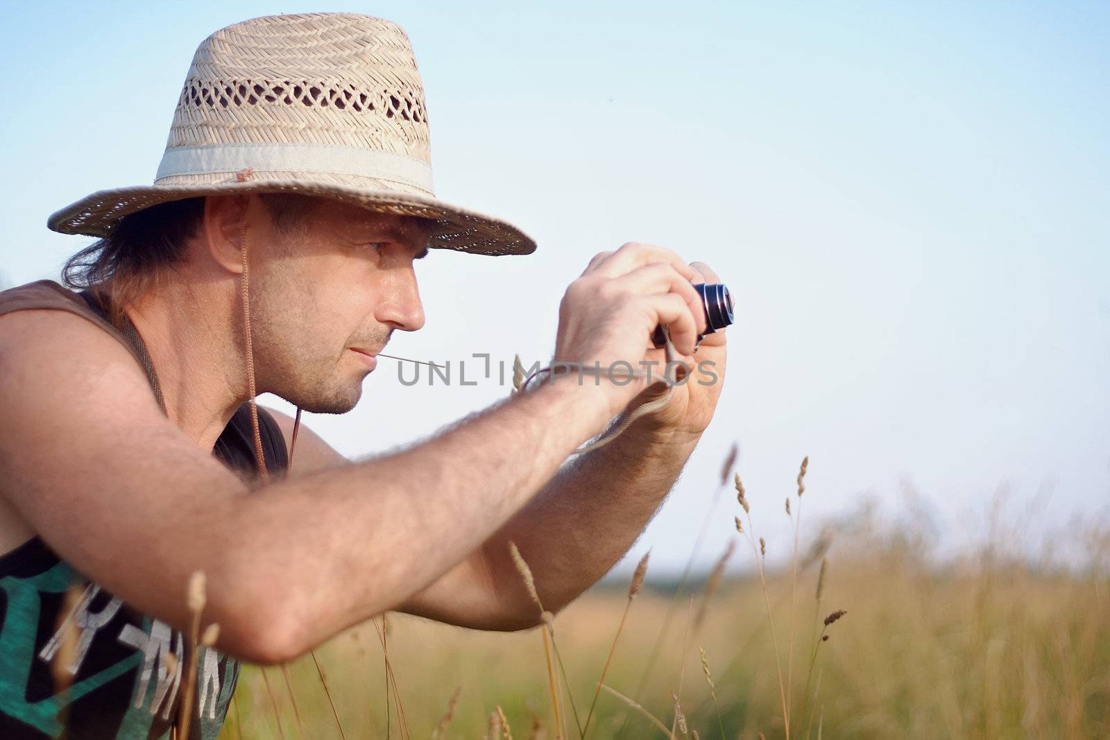 The man in a straw hat with the camera has a rest outdoors