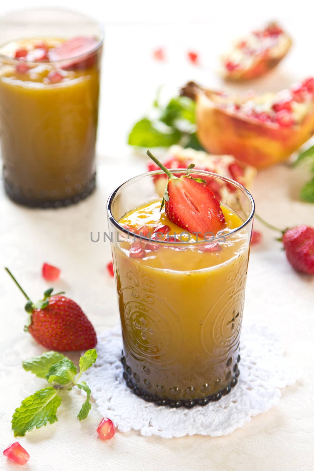 Mango and pineapple smoothie with fresh pomegranate and strawberry on top