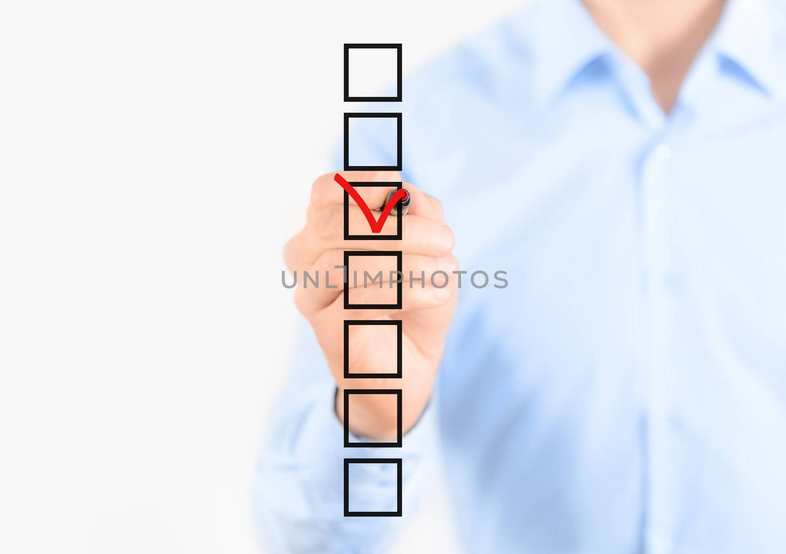 Young businessman checking mark on checklist with marker. Isolated on white.