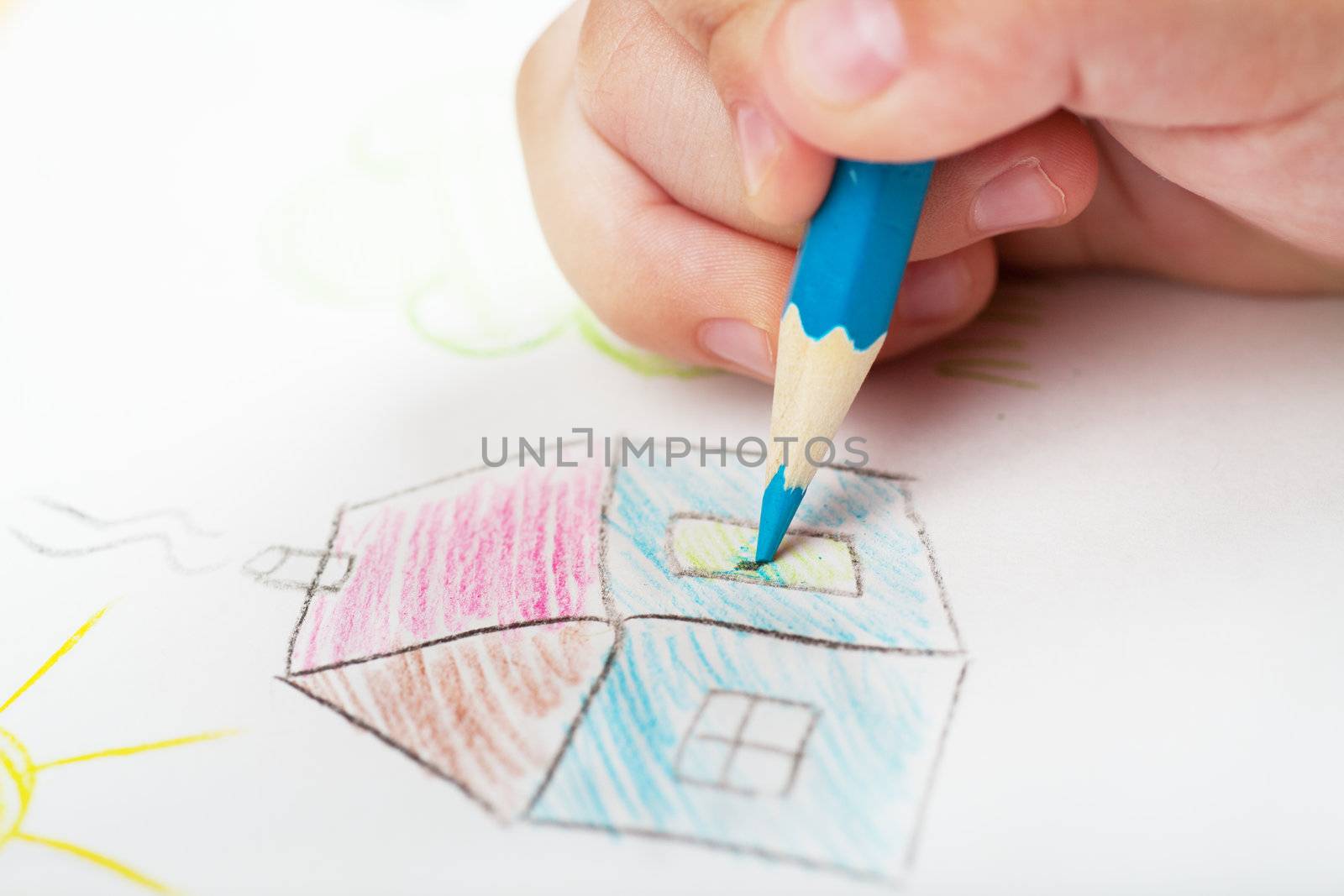 Child's hand drawing a house with blue pen