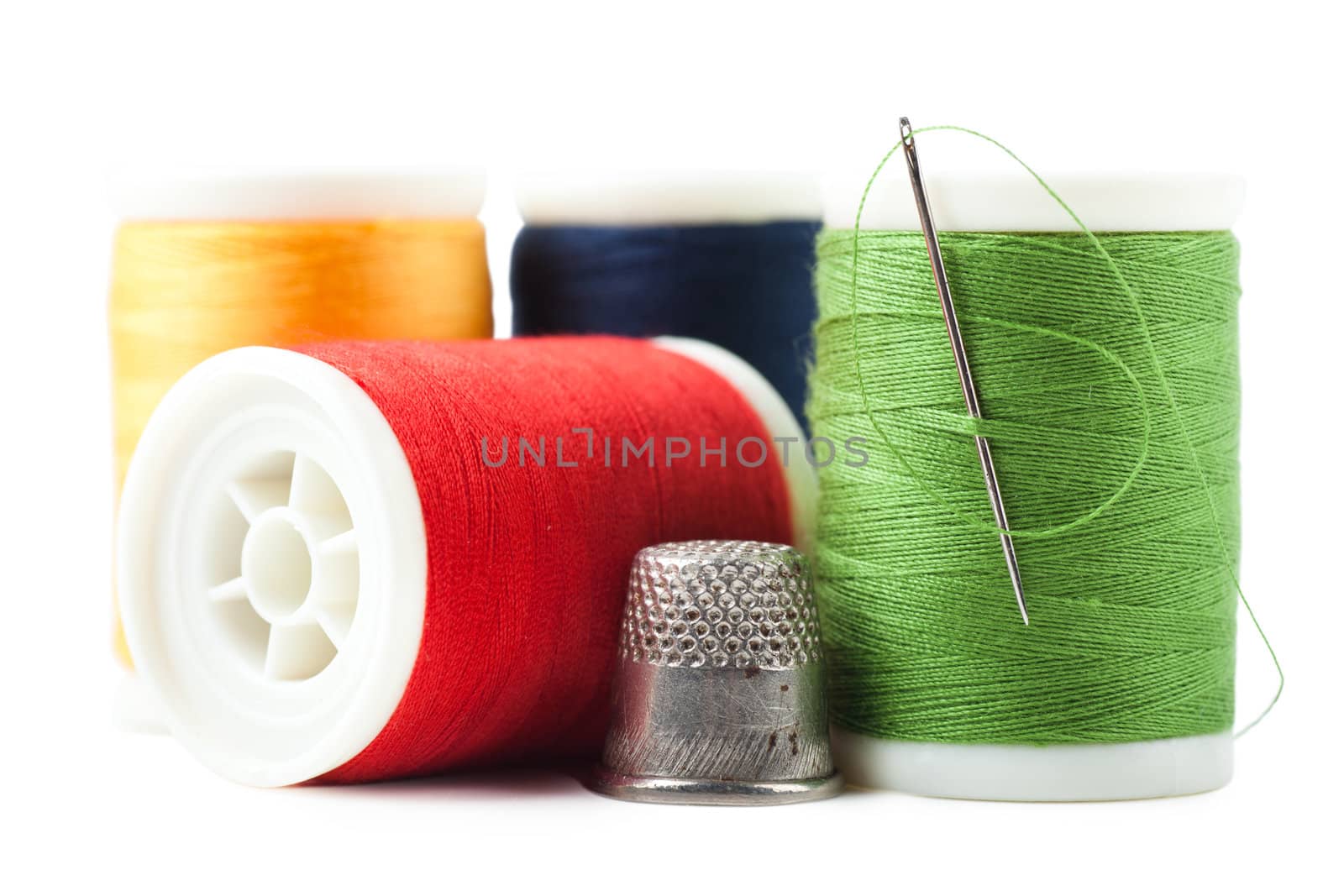 Colorful thread spools with green thread and needle