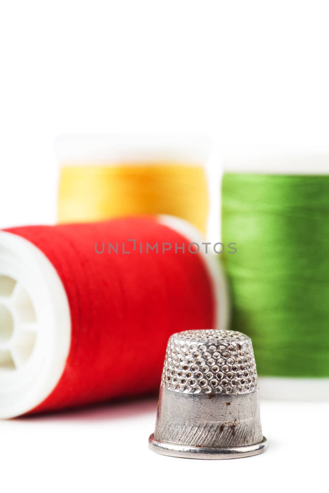 Closeup view of thimble and colorful spools over white background