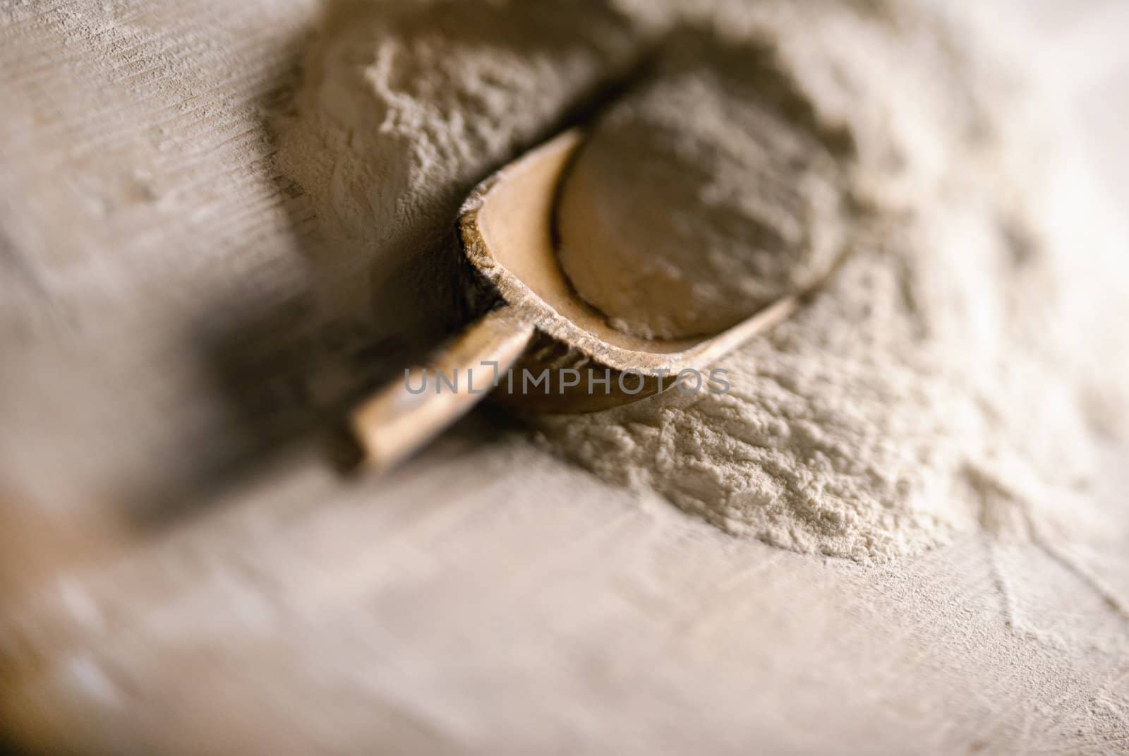 Bakery wooden scoop in a heap of wholegrain flour with a tilt shift lens