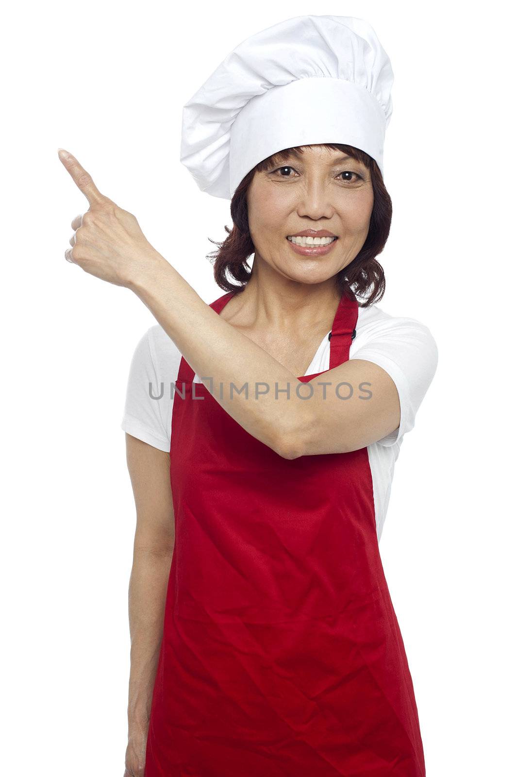 Female chef in uniform pointing away. Copy space concept. Isolated over white