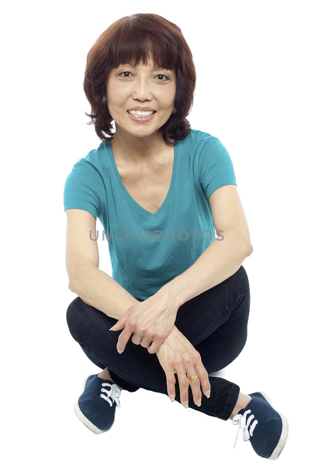 Casual teen girl sitting criss cross on the floor isolated against white background