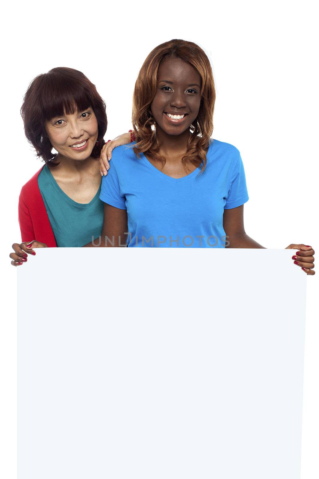 Young ethnic friends behind blank ad board smiling at camera