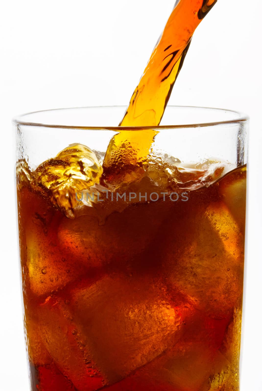 Cola is pouring into glass on white background