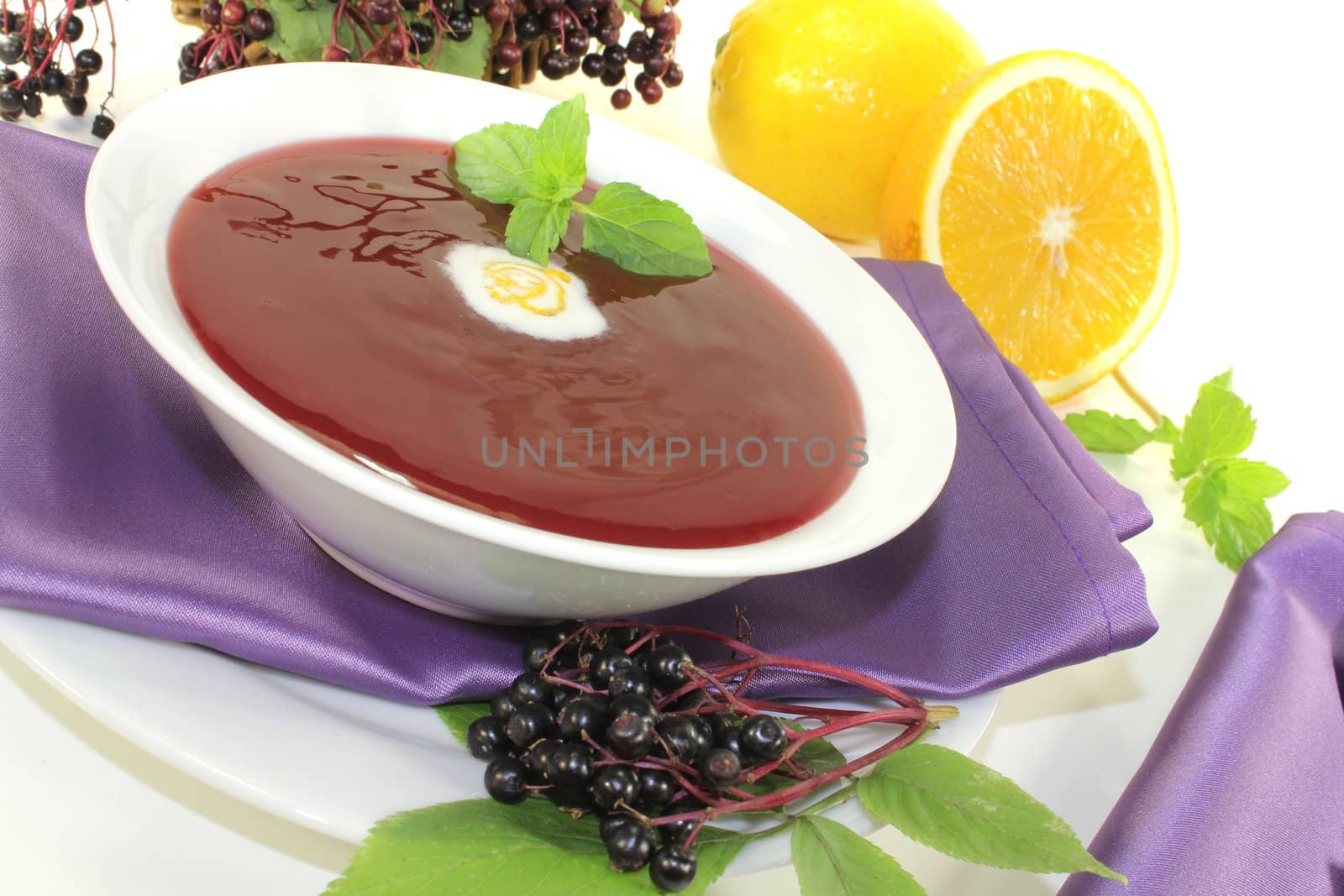 healthy elderberry soup with blobs of cream and mint on a bright background