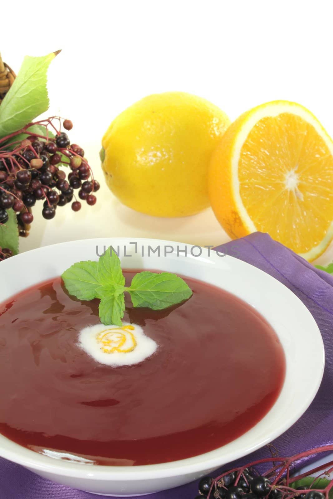elderberry soup with dollop of whipped cream and mint on a light background