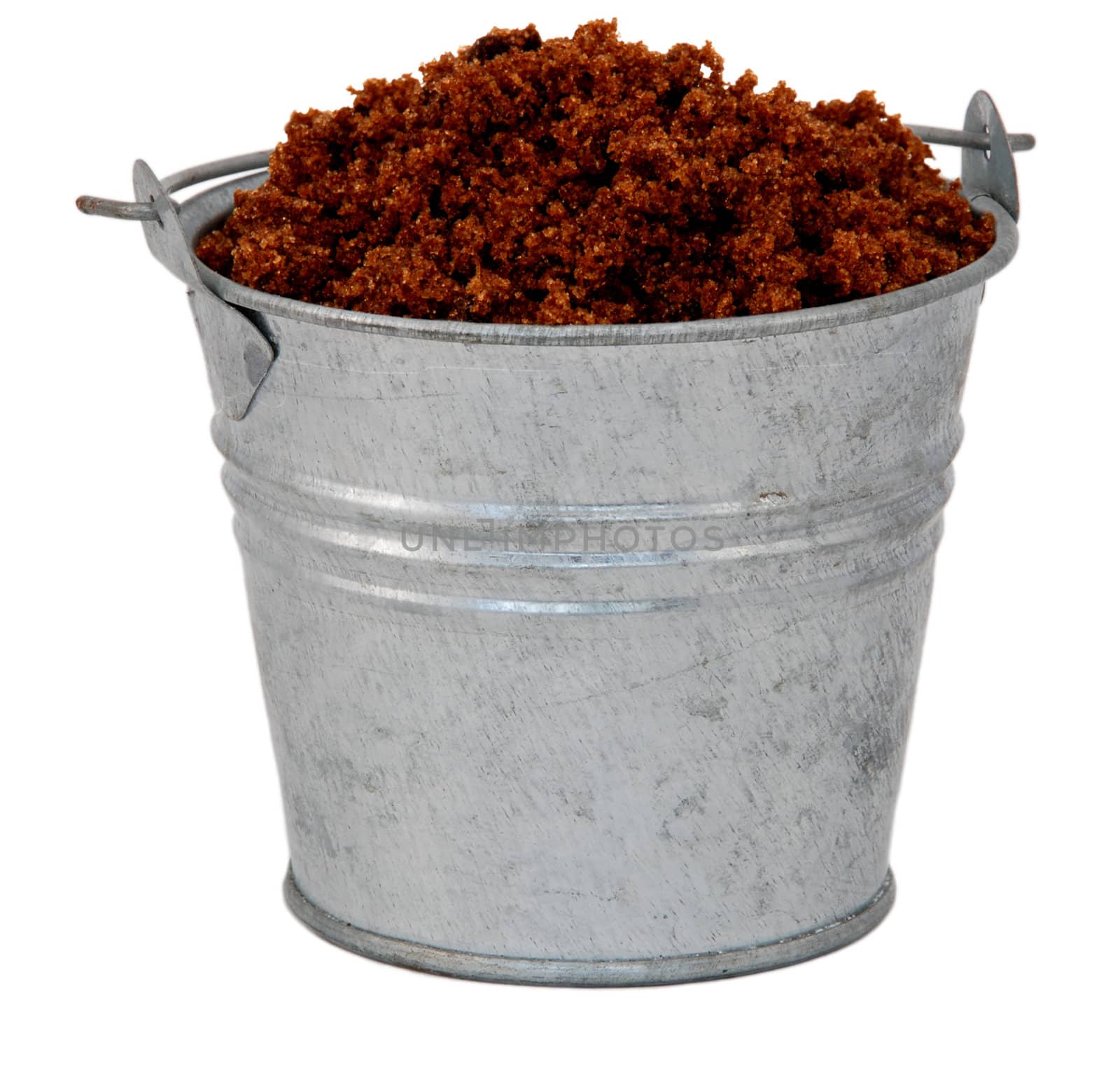 Dark brown soft / muscovado sugar in a miniature metal bucket, isolated on a white background