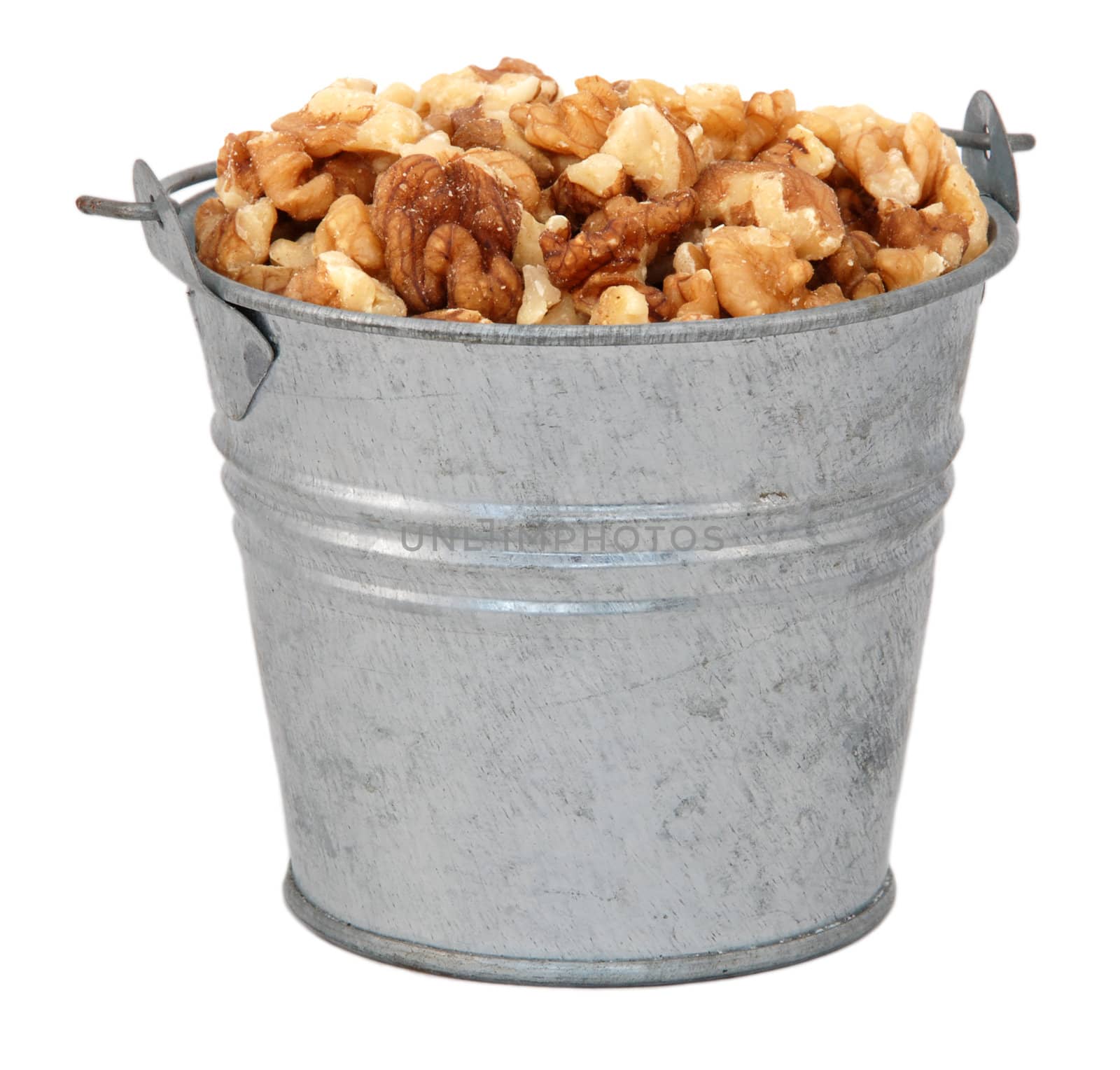 Chopped walnuts in a miniature metal bucket, isolated on a white background