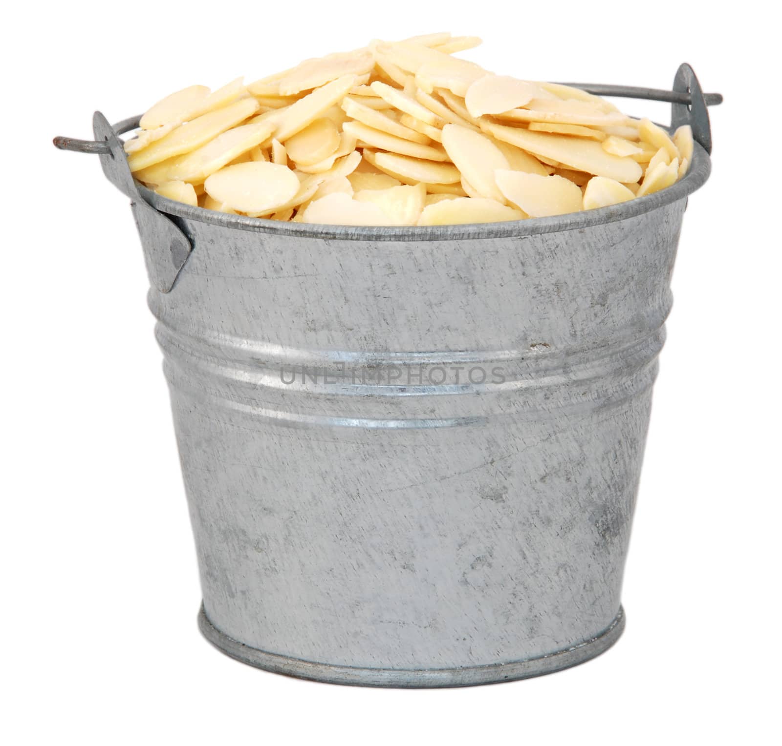 Flaked almonds in a miniature metal bucket, isolated on a white background