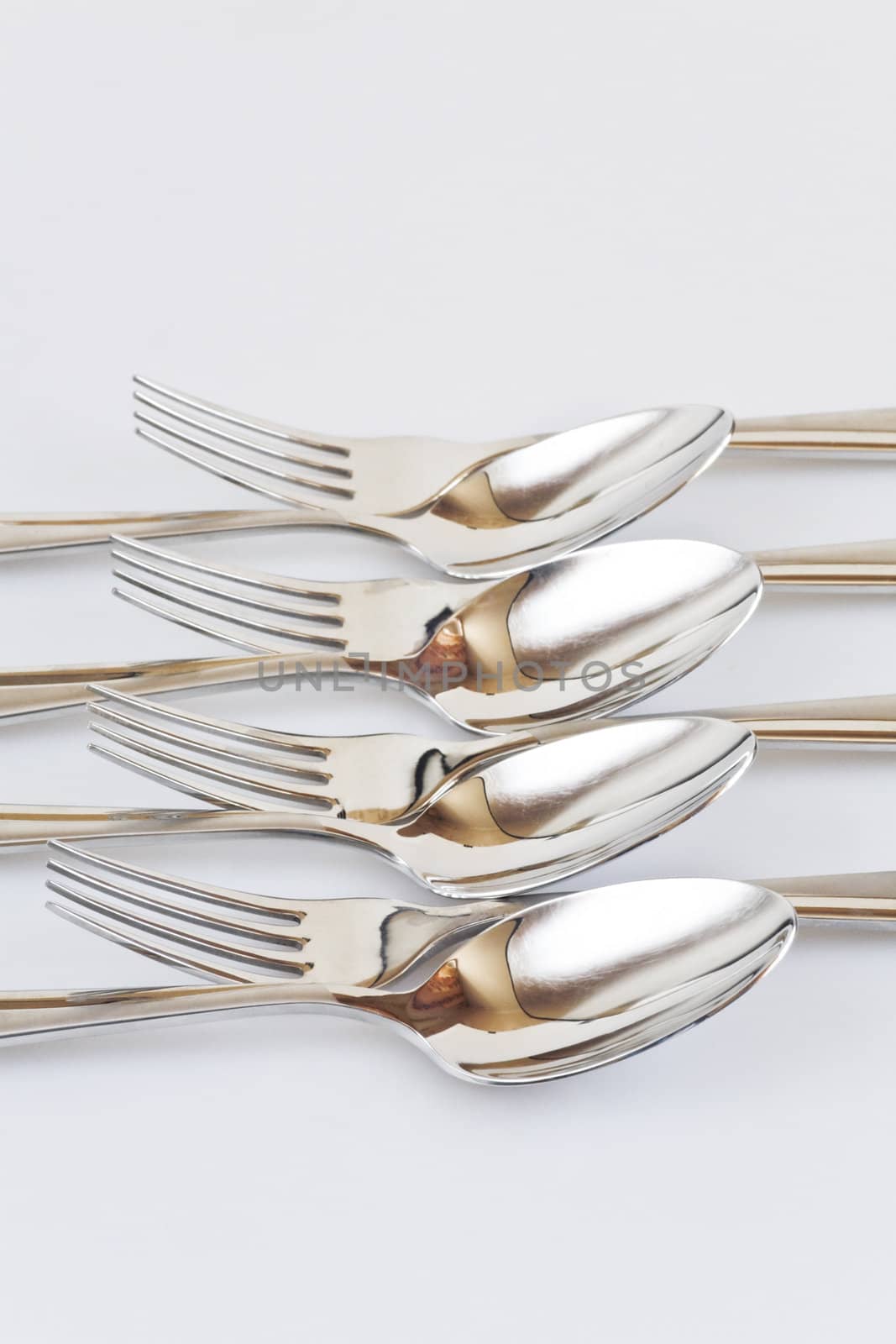 Set of forks and spoons abreast on a white background