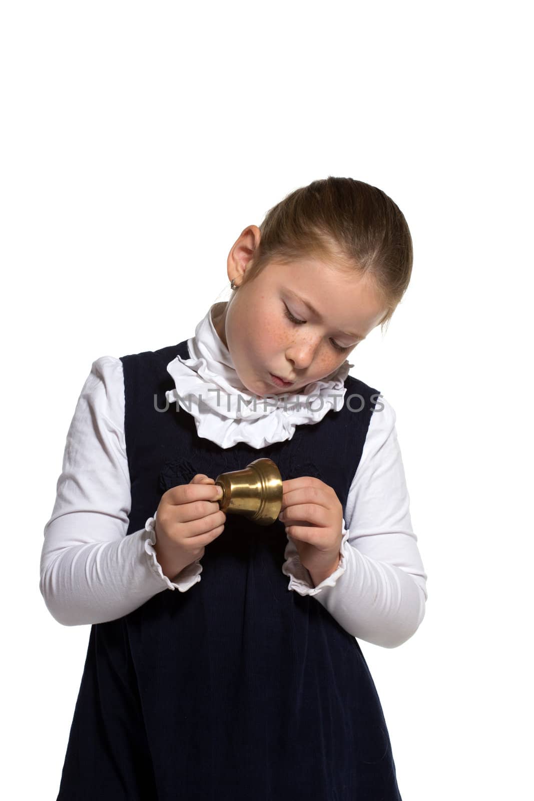 Young school girl looking to golden bell on white background