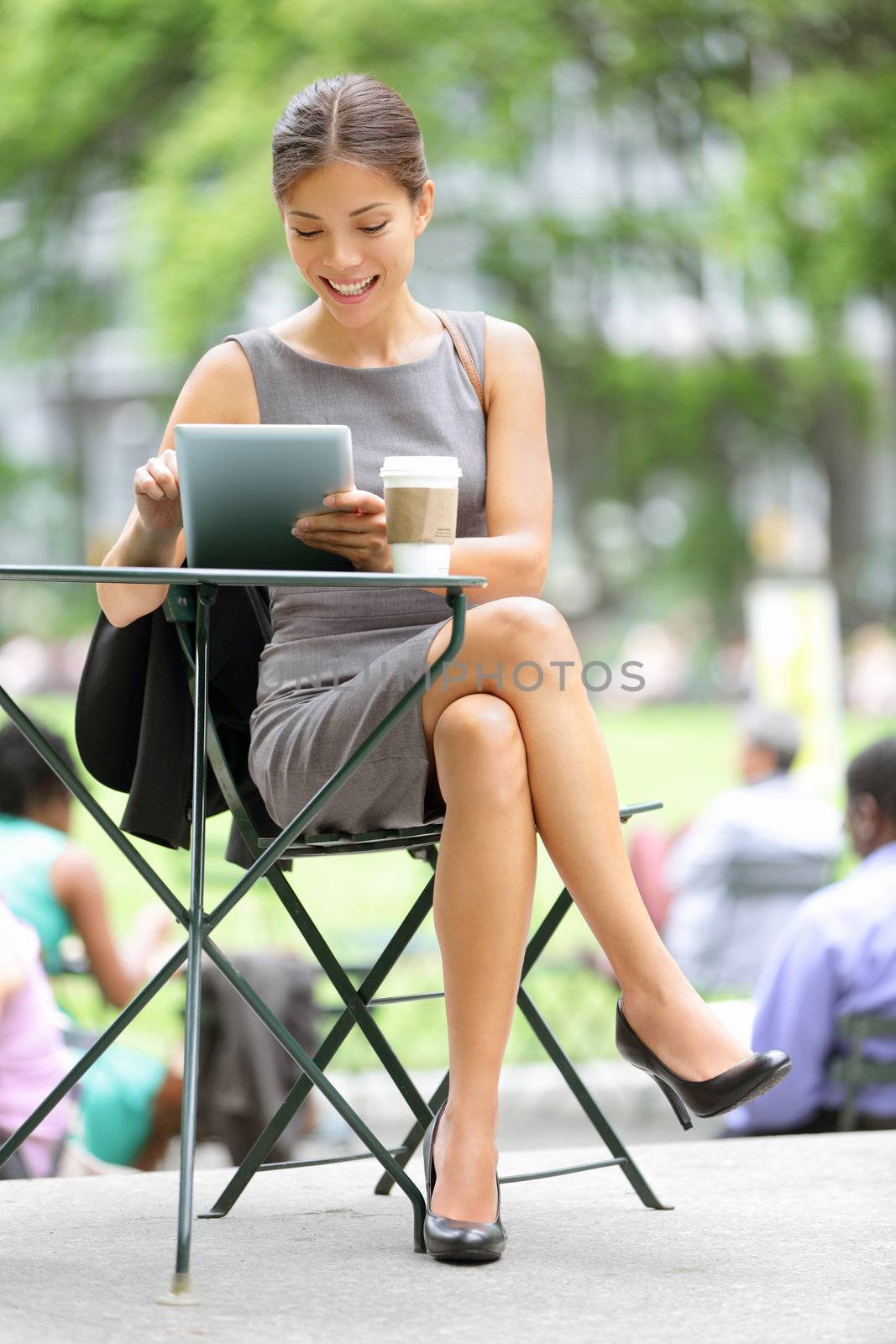 Businesswoman on break in park. Young professional business woman using tablet computer in Bryant Park, New York City, USA. Mixed race Asian Chinese / Caucasian female model.