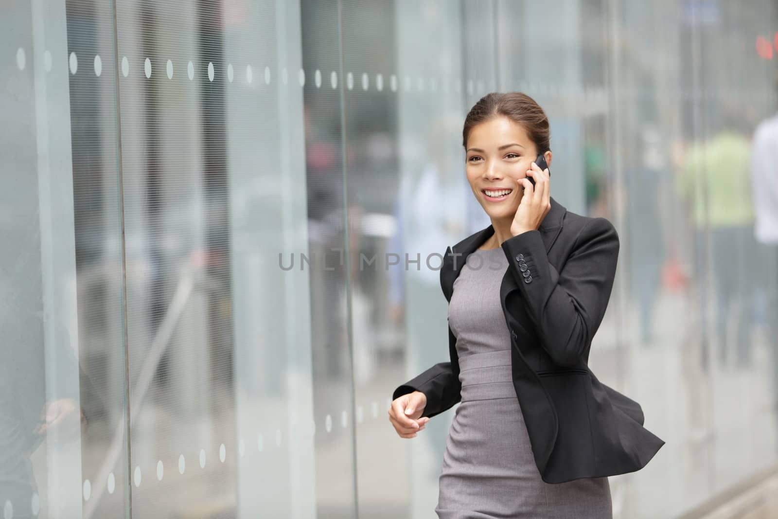 Businesswoman on cellphone running while talking on smart phone. Happy smiling mixed race Asian / Caucasian business woman busy. Image from Manhattan, New York City.