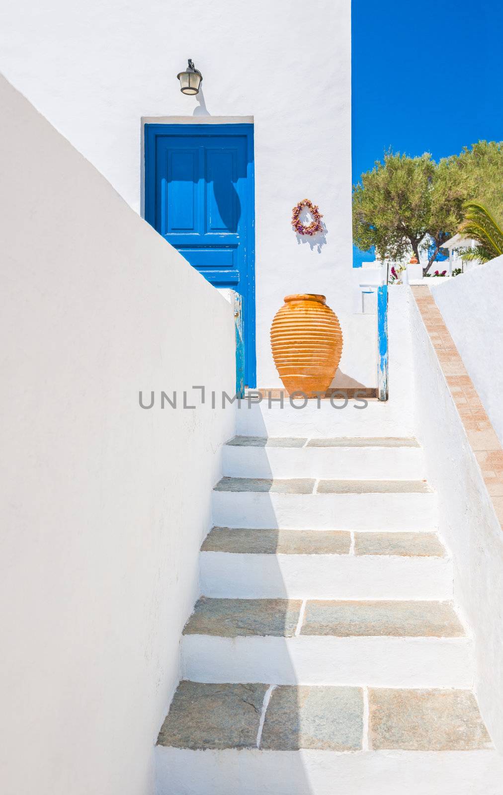 Staircase and ceramic vase near blue door, Sifnos, Greece by akarelias