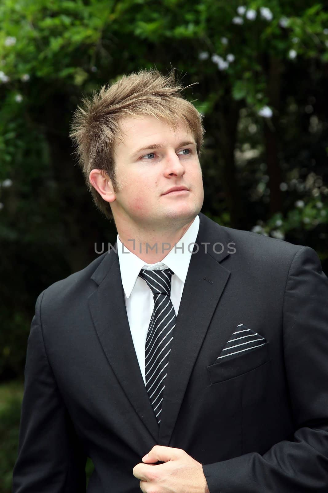 Handsome young bridegroom in a black suit and tie