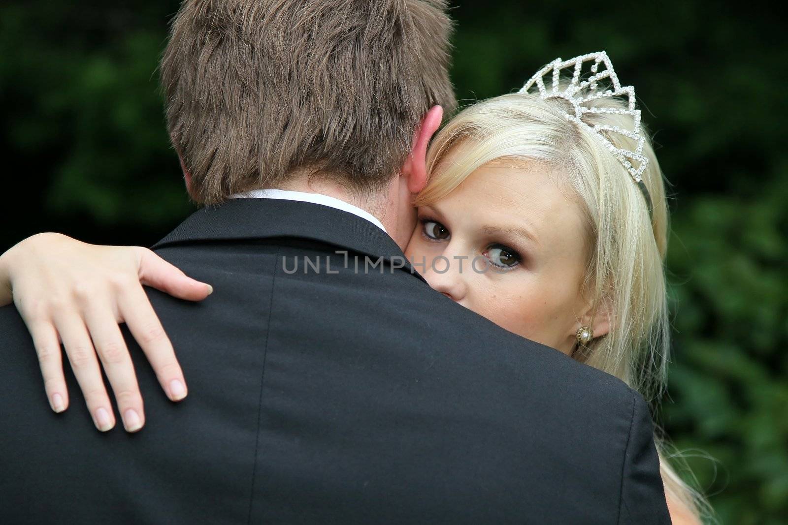 Lovely bride embracing her husband and looking over his shoulder